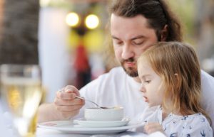 Dad feeding soup to daughter